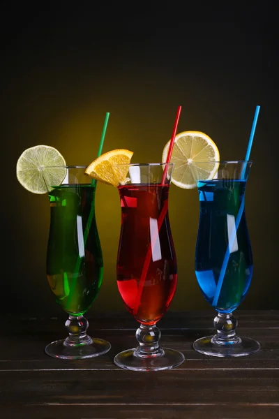 Glasses of cocktails on table on dark yellow background — Stock Photo, Image