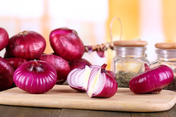 Skär lök på skärbräda på träbord, på ljus bakgrund — Stockfoto