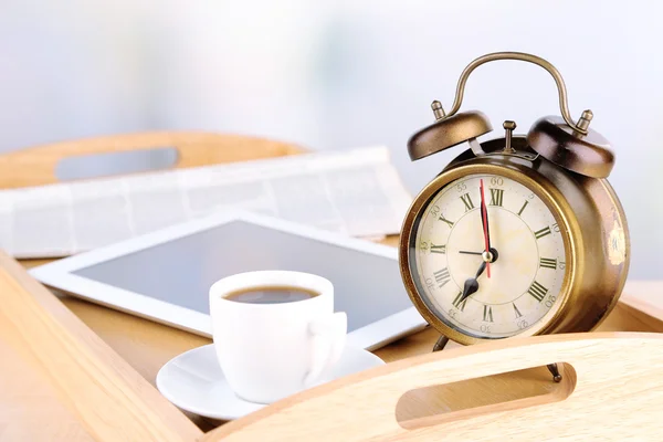 Tablet, newspaper, cup of coffee and alarm clock on wooden tray Royalty Free Stock Photos