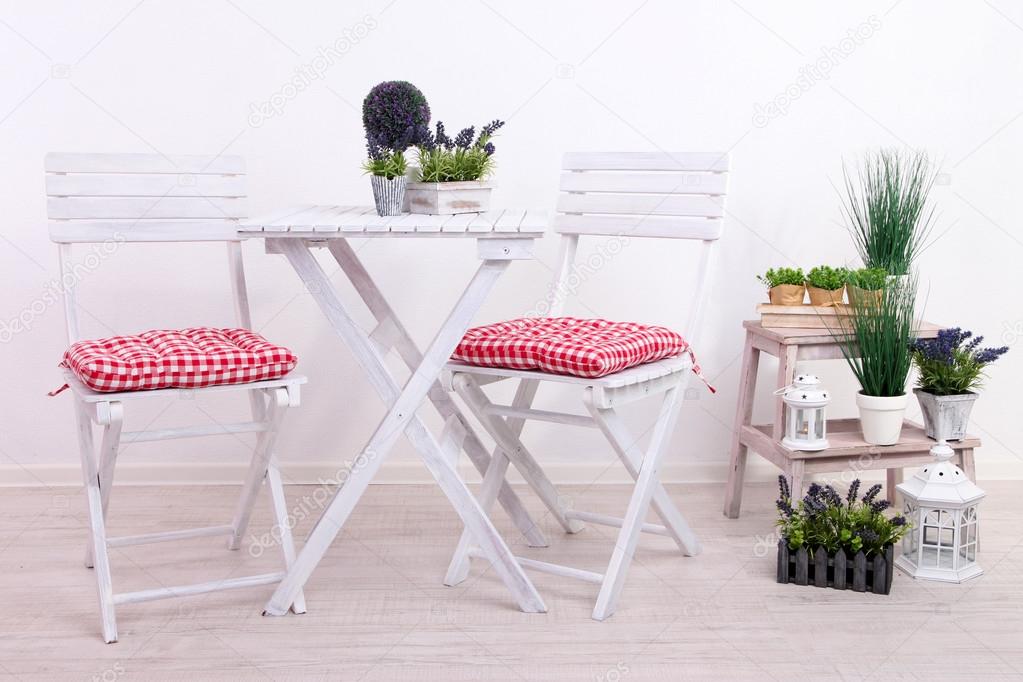 Garden chairs and table with flowers on wooden stand on white background