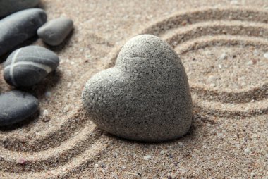 Gri zen stone kum arka plan üzerinde kalp şeklinde