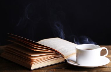 sıcak kahve ile masaya koyu arka plan üzerinde kitap