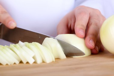 Mutfak arka planında soğan doğrayan kadın elleri.