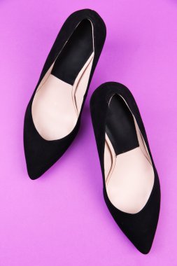 Güzel siyah kadın ayakkabıları, mor arka planda.