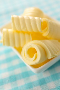 Mavi masa örtüsü üzerinde kase taze tereyağı bukleler