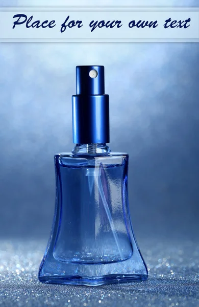 Naiset hajuvesi kauniissa pullossa sinisellä pohjalla — kuvapankkivalokuva