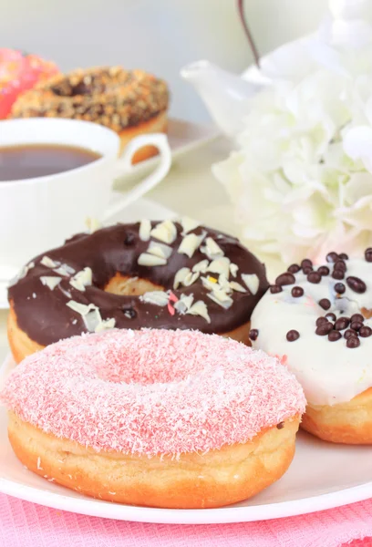 Doce donuts com xícara de chá na mesa em fundo claro — Fotografia de Stock