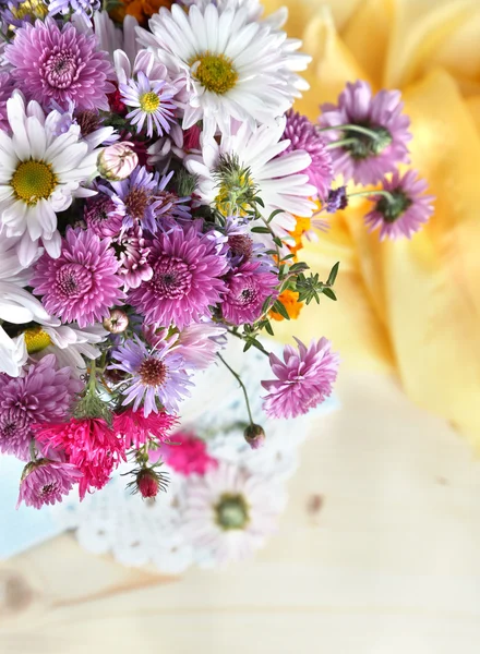 Flores silvestres cerca de tela amarilla sobre fondo de madera — Foto de Stock