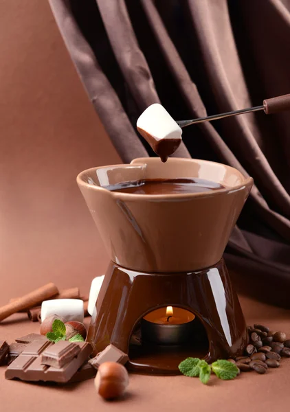 Chocolate fondue with marshmallow candies, on brown background — Stock Photo, Image