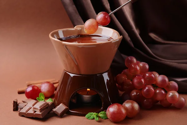 Chocolate fondue with fruits, on brown background — Stock Photo, Image