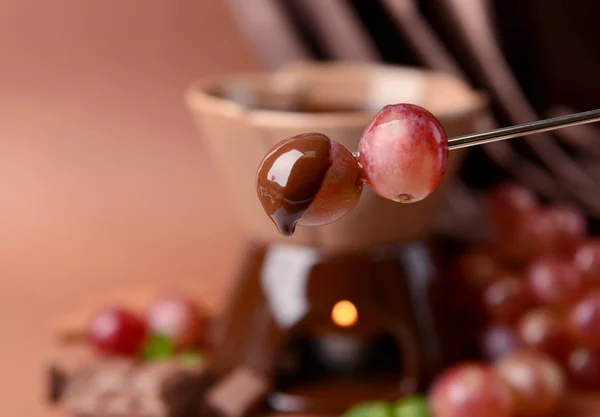 Шоколадний фонтан з фруктами, на коричневому фоні — стокове фото