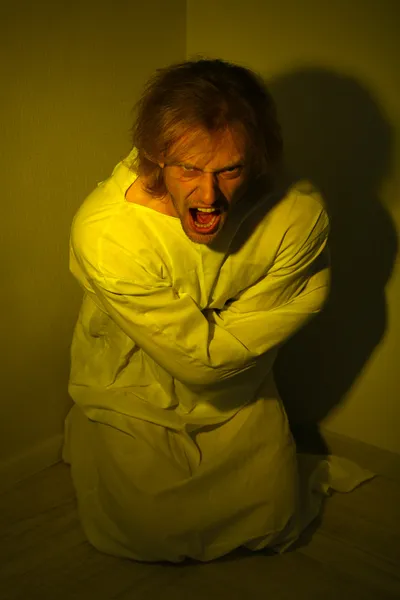 Mentally ill man in strait-jacket in room corner — Stock Photo, Image