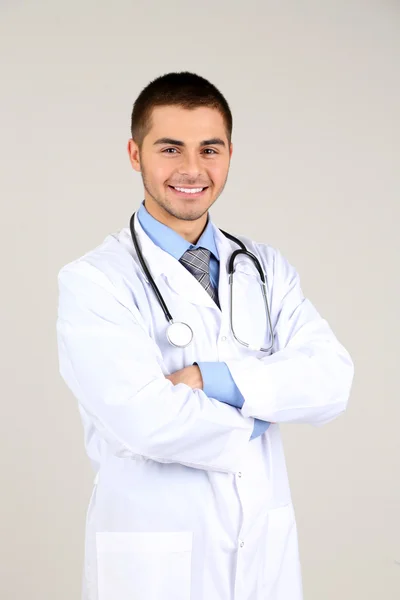 Male Doctor standing on gray background — Stock Photo, Image