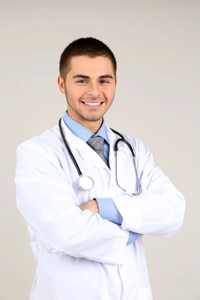 Mężczyzna lekarz stojący na szarym tle — Zdjęcie stockowe