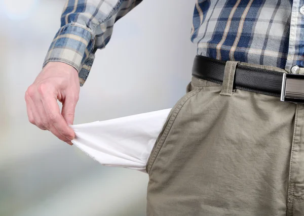 Mann zeigt seine leere Tasche auf hellem Hintergrund — Stockfoto