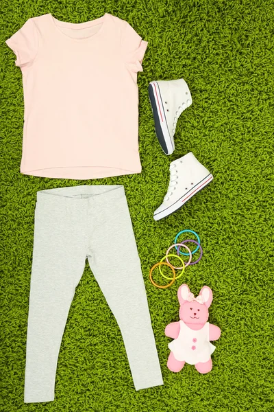 Красивая одежда для маленькой девочки на зеленом ковре — стоковое фото