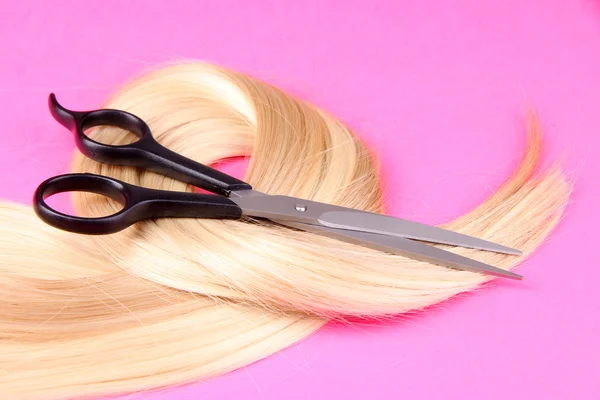 Dlouhé blond vlasy s nůžkami na růžovém pozadí — Stock fotografie