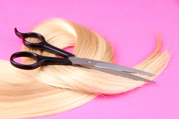 Long blond hair with scissors on pink background — Stock Photo, Image