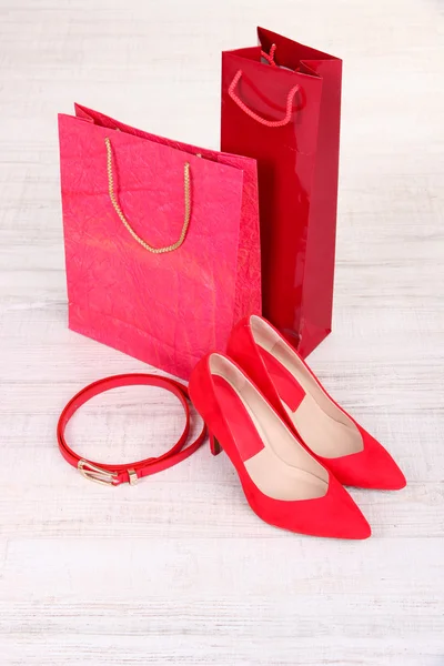 Belles chaussures féminines rouges, ceinture et sacs de magasin — Photo