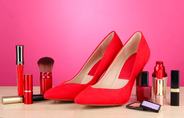 Beautiful red female shoes with cosmetics, on pink background — Stock Photo, Image