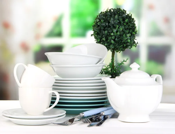 Clean dishes on table on window background — Stock Photo, Image