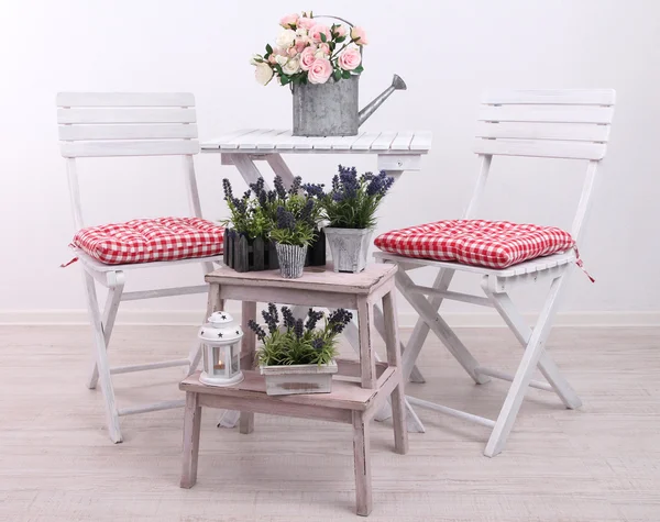 Cadeiras de jardim e mesa com flores em suporte de madeira sobre fundo branco — Fotografia de Stock