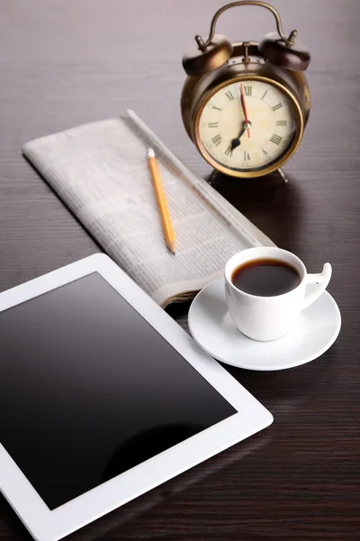 Tablet, jornal, xícara de café e despertador na mesa de madeira — Fotografia de Stock