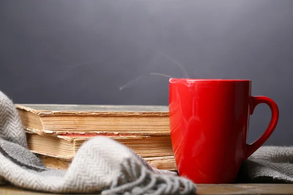 Taza de té caliente con libros y cuadros sobre la mesa sobre fondo oscuro — Foto de Stock