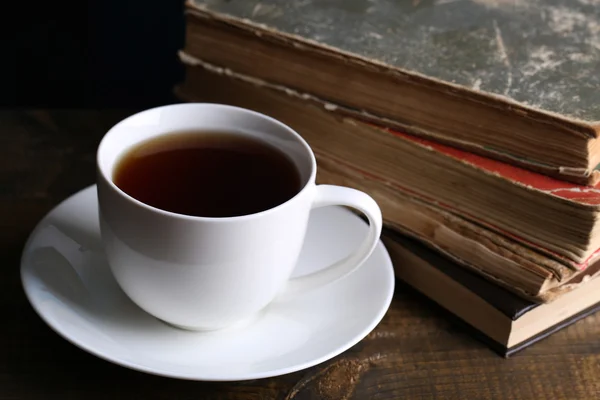 Taza de té caliente con libros en la mesa de cerca —  Fotos de Stock