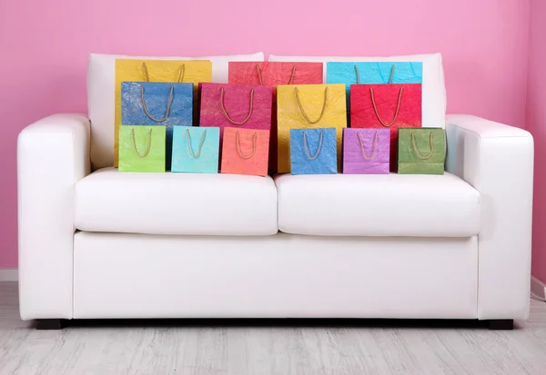 Borse colorate per la spesa sul divano, sullo sfondo della parete a colori — Foto Stock
