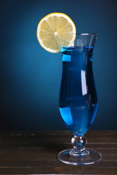 Glass of cocktail on table on dark blue background — Stock Photo, Image