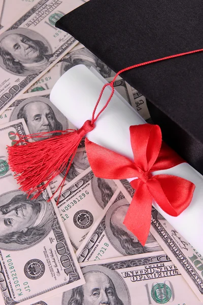 Graduation hat and scroll on money background — Stock Photo, Image