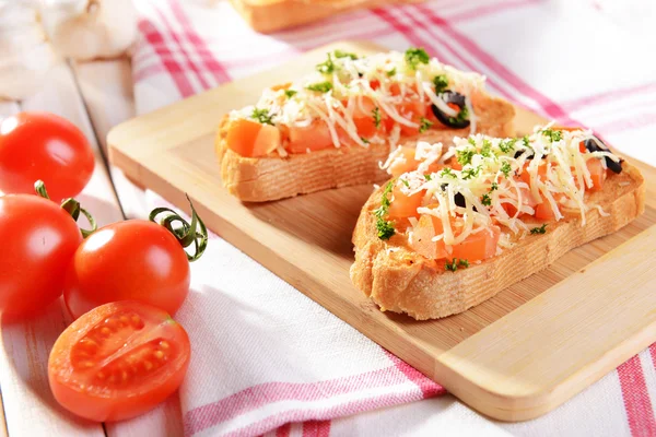 Deliciosa bruschetta con tomates en la tabla de cortar de cerca — Foto de Stock