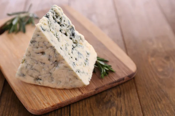 Smakelijke blauwe kaas met rozemarijn, op houten tafel — Stockfoto