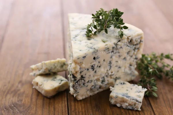 Tasty blue cheese with thyme, on wooden table — Stock Photo, Image