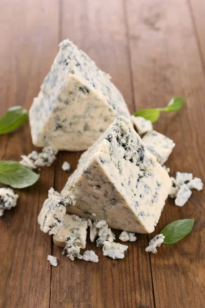 Queijo azul saboroso com manjericão, na mesa de madeira — Fotografia de Stock