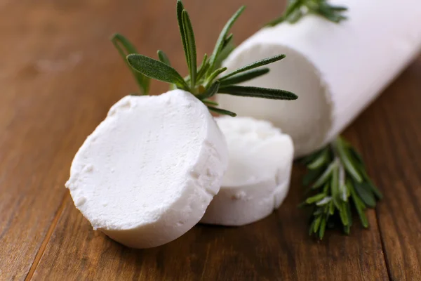 Tasty bushe cheese with rosemary, on wooden table — Stock Photo, Image