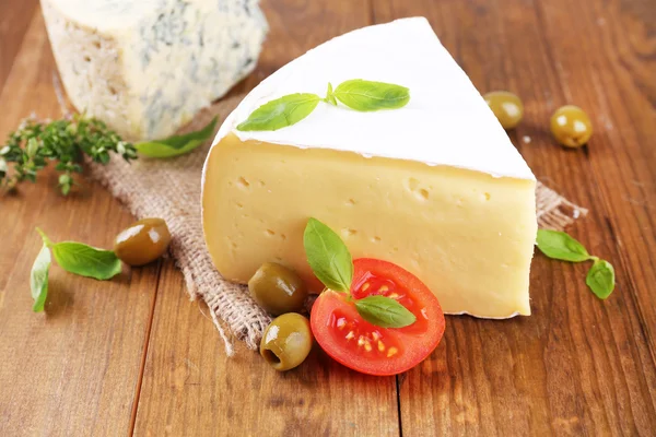 Sabroso queso Camembert con tomate, albahaca y aceitunas, sobre mesa de madera — Foto de Stock