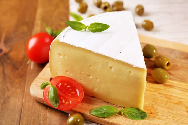 Sabroso queso Camembert con tomates, aceitunas y albahaca, sobre mesa de madera — Foto de Stock