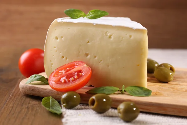 Chutný sýr camembert s rajčaty, olivami a bazalkou, na dřevěný stůl — Stock fotografie