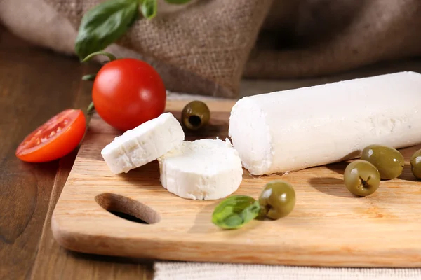 Savoureux fromage bushe aux tomates, olives et basilic, sur planche à découper — Photo