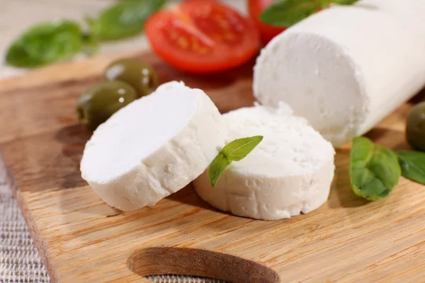 Ízletes bushe sajt, paradicsom, olajbogyó, bazsalikom, vágódeszka — Stock Fotó