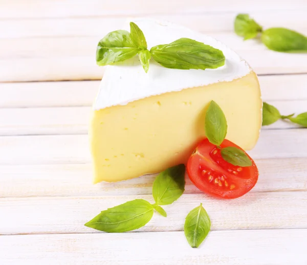 Sabroso queso Camembert con albahaca y tomates, sobre mesa de madera — Foto de Stock