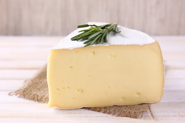 Sabroso queso Camembert con romero, sobre mesa de madera —  Fotos de Stock