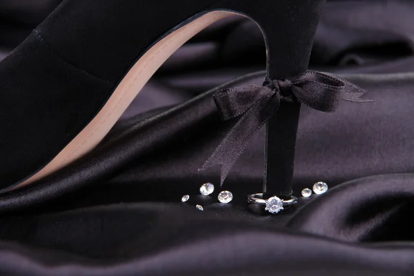 Hermoso anillo en el talón de zapato femenino negro, sobre fondo de seda —  Fotos de Stock