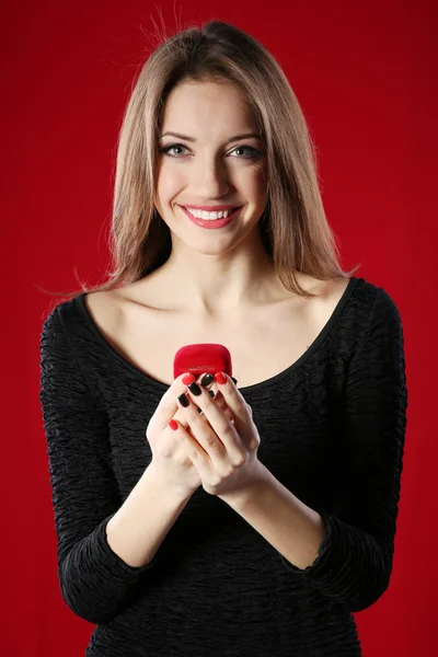 Girl looks at box with wedding ring on color background — Stock Photo, Image