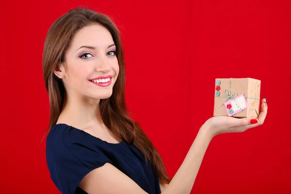 Donna attraente con scatola regalo, su sfondo colore — Foto Stock