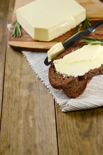 Fatia de pão de centeio com manteiga na tábua de corte de madeira — Fotografia de Stock