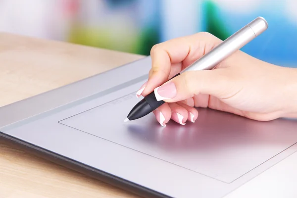 Female hand using graphics tablet on table on bright background — Stock Photo, Image