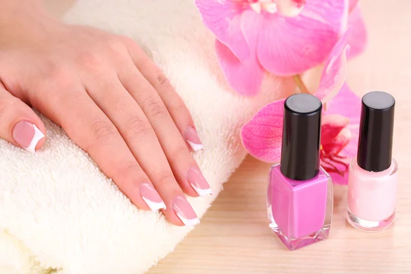 Hermosas manos de mujer con manicura francesa y flores sobre fondo de madera —  Fotos de Stock